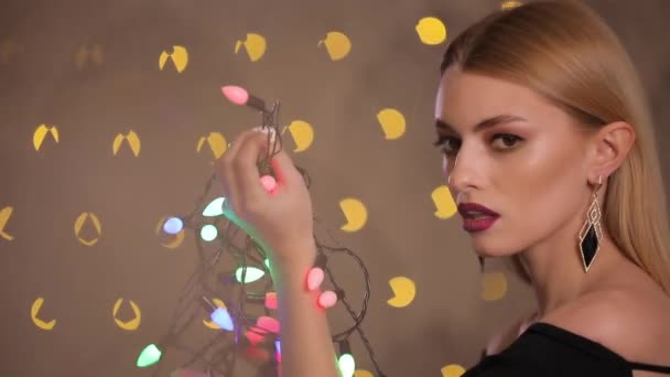 Bonita modelo de moda juega con guirnalda eléctrica en luces amarillas fondo bokeh, cámara lenta — Vídeo de stock