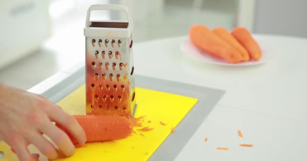 Hombre ralla zanahoria en rallador de acero inoxidable — Vídeos de Stock