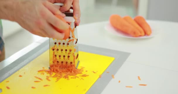 Ο άνθρωπος σχάρες καρότο στον τρίφτη από ανοξείδωτο χάλυβα — Αρχείο Βίντεο