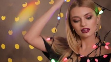 Güzel manken arka planda sarı ışık bokeh, yavaş hareket elektrik garland ile çalış