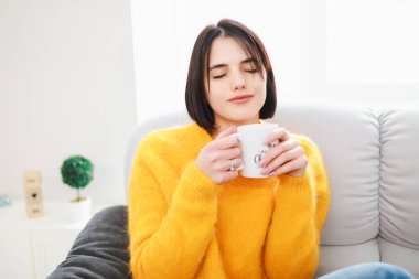 Sabah hafta sonu dinlenme günü sova üzerinde oturan dairede çay bardağı içme kadın