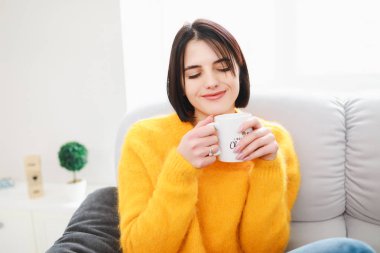 Sabah hafta sonu dinlenme günü sova üzerinde oturan dairede çay bardağı içme kadın