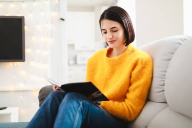 Kadın okuma kitabı evde rahat koltukta oturan bir dinlenme günü