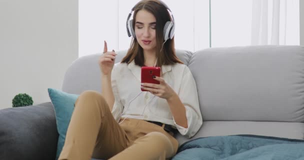 Woman listening a music at home in big headphones — Stock Video