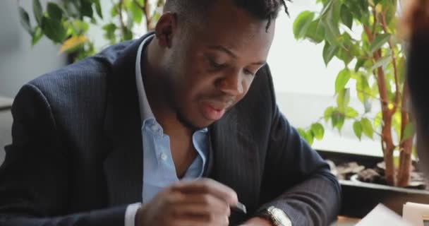 Afrikai üzletember aláírja a szerződést egy kávézóban — Stock videók