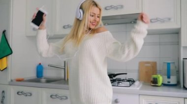 Kaygısız genç kadın mutfakta müzik dans