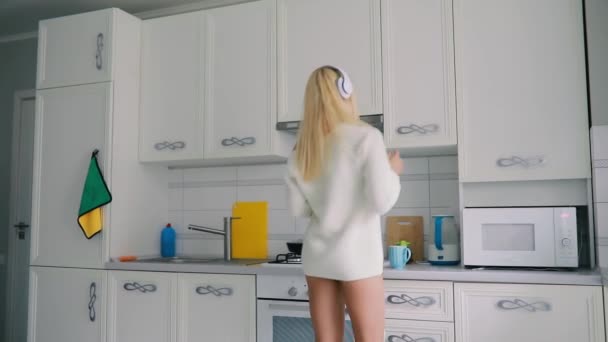 キッチン喫茶 スローモーションのスマート フォンを保持している音楽を聴くことで踊るセクシーな屈託のない若い女性 — ストック動画