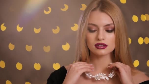 Fotomodel zet op halsketting in geel lights bokeh, slow-motion — Stockvideo