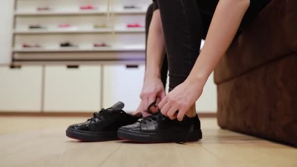 Vrouw stropdas schoenveters op laarzen in een winkel — Stockvideo