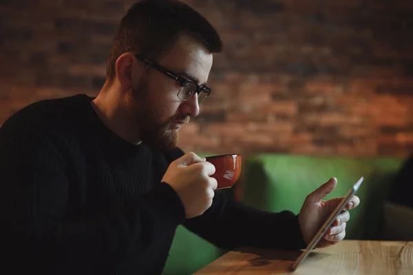 Man having coffee break while using tablet