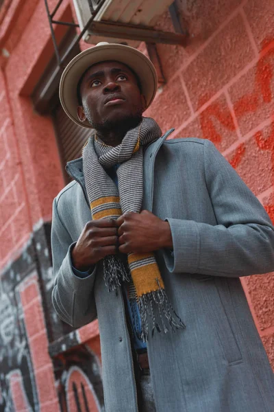 コートと赤い背景の建物で帽子でアフリカ系アメリカ人のストリートの肖像 — ストック写真