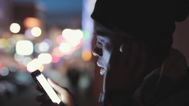 Close-up van Afrikaanse man luisteren muziek in oortelefoons bij nacht — Stockvideo