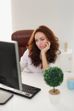 Güzel iş kadını beyaz ofiste bilgisayar monitörü seyir çalışma