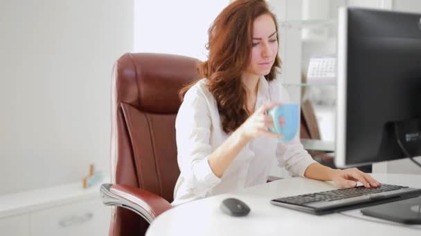 Schöne Geschäftsfrau, die im Büro arbeitet und Kaffee trinkt — Stockvideo