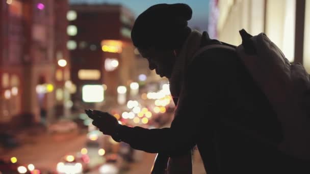 Sziluettjét az ember éjjel használ smartphone, a fülhallgató — Stock videók