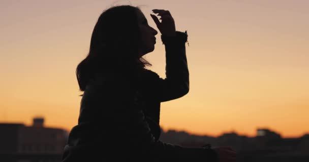 Silhueta de mulher pensando no futuro ao pôr do sol na cidade — Vídeo de Stock