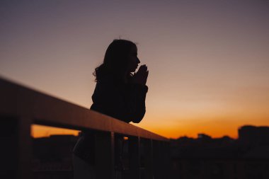 Kadın silüeti düşünüyor ve gelecekle ilgili günbatımında şehirde rüyalar.