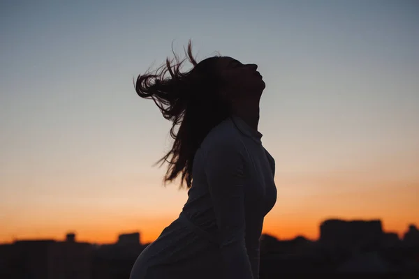 Silhouette of woman toss her hair at sunset in the city