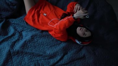 Kız yatakta, üstten görünüm yatarken kulaklık müzik dinleme