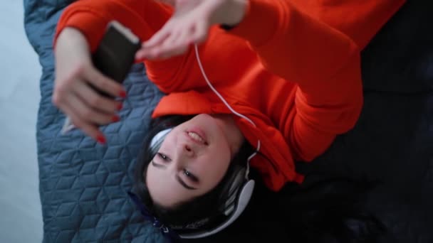 Chica uso teléfono inteligente acostado en la cama, vista superior — Vídeo de stock