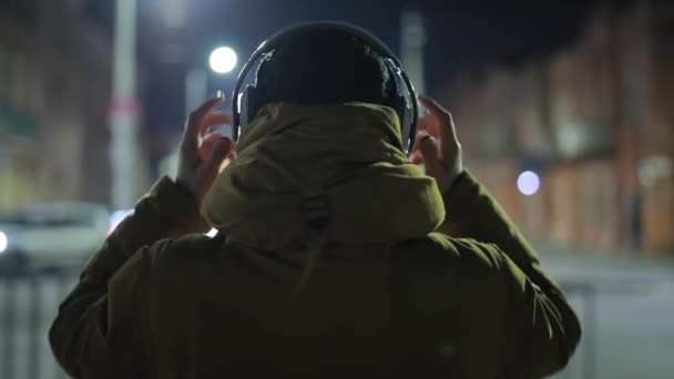 Hombre irreconocible escuchando música en auriculares en la ciudad nocturna — Vídeos de Stock