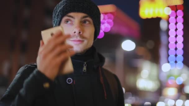Человек отвечает на входящий звонок в ночном городе — стоковое видео