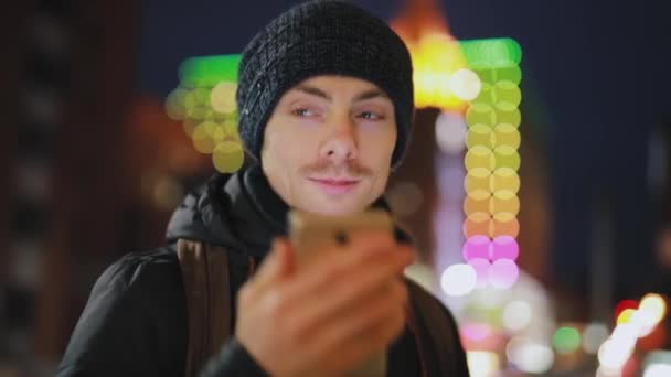 El hombre responde a la llamada entrante en una ciudad nocturna — Vídeos de Stock