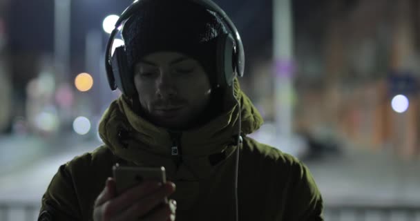 Muž ukazuje prázdnou zelenou obrazovku smartphone v noční město — Stock video