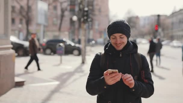 Az ember használ smartphone séta a város utca — Stock videók