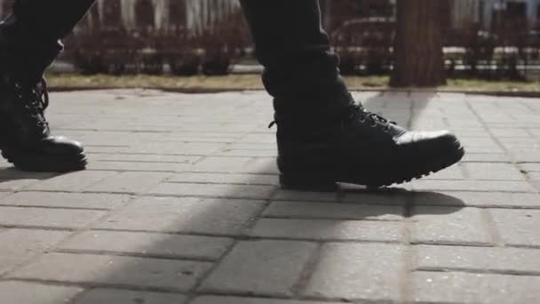 Мужские ноги в сапогах прогуливаясь по городской улице — стоковое видео