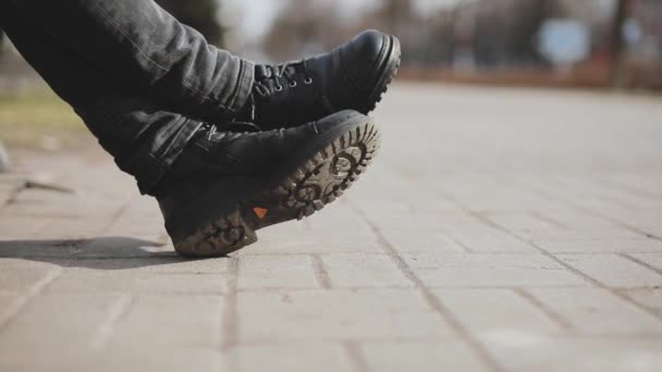 Masculino piernas en botas relajante sentado en la calle de la ciudad — Vídeo de stock