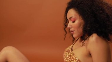 Turuncu arka planda stüdyoda poz güzel kadın