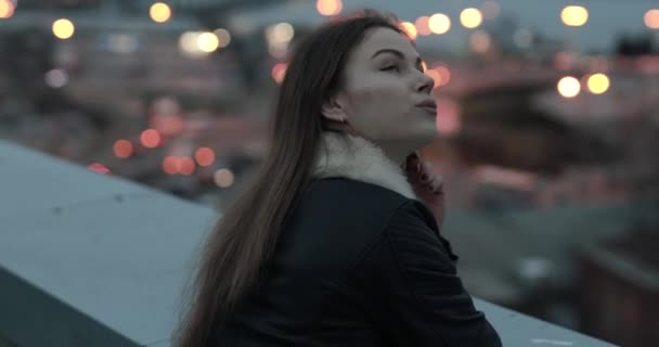 Jonge vrouw kijkt uit naar de avond city scape — Stockvideo