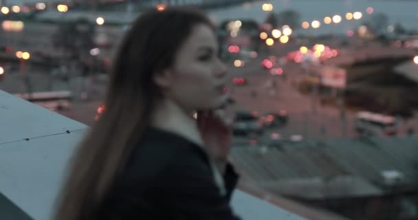 Молодая женщина с нетерпением ждет вечернего городского пейзажа — стоковое видео