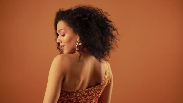 Vacker kvinna poserar i studion på orange bakgrund — Stockvideo