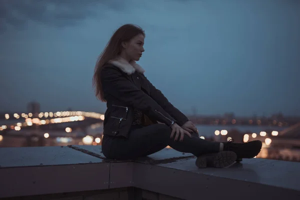 Silhouet van alleen vrouw zittend op het dak, de stad op de achtergrond — Stockfoto