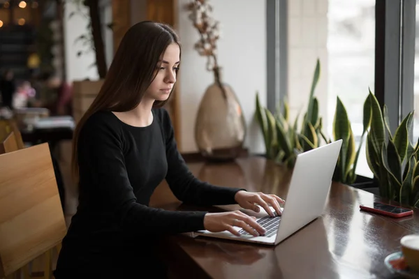 Vrouw die werkt door laptop zitten in een cafe — Stockfoto