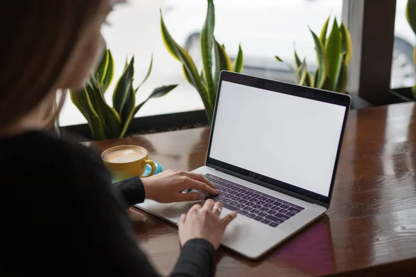 Kvinne frilanser som arbeider med laptop på kafe, tom skjerm på pc stockfoto