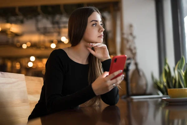 Nainen käyttää mobiili älypuhelin kahvilassa — kuvapankkivalokuva