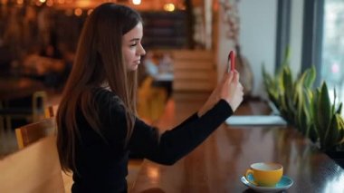 Kadın yanında smartphone kafede oturan bir selfie yapmak
