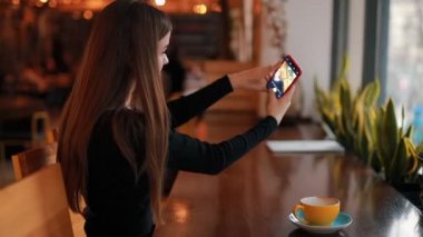 Kadın blogger kahve kafede oturup onu sosyal hesap için fotoğraf çekimi
