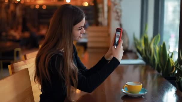 Woman blogger photographing cup of coffee for her social account sitting in cafe — Stock Video