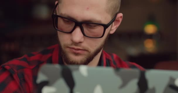 Άνθρωπος σε γυαλιά που εργάζονται από φορητό υπολογιστή σε κοντινό καφέ — Αρχείο Βίντεο