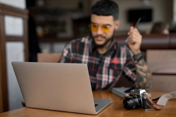 Stylish handsome man freelancer looking at laptop computer in cafe