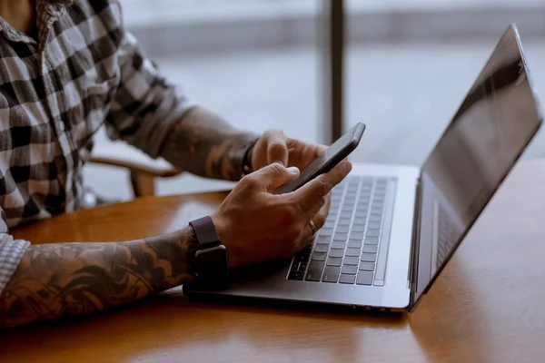 Mâinile unui om de afaceri care lucrează cu laptop-ul și smartphone-ul în cafenea — Fotografie, imagine de stoc