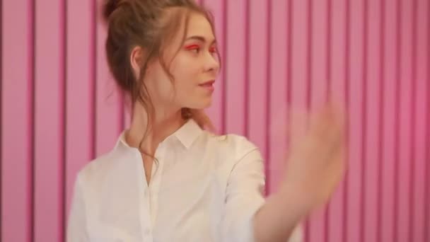 Дівчина позує біля рожевої стіни — стокове відео