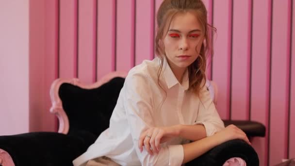Молодая модель позирует на стуле в розовой студии — стоковое видео