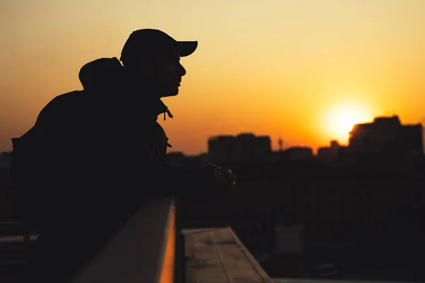 A silhueta de homem de sonho em um pôr-do-sol de cidade olha em volta — Fotografia de Stock