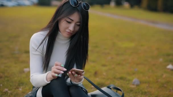 Asiatin nutzt Anwendung in Smartphone-Outdoor — Stockvideo