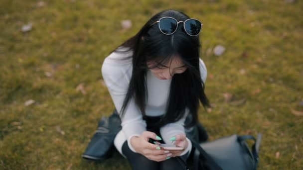 Asiatin nutzt Anwendung in Smartphone-Outdoor — Stockvideo